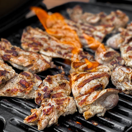 Grilled chicken pieces on a barbecue grill with visible grill marks.