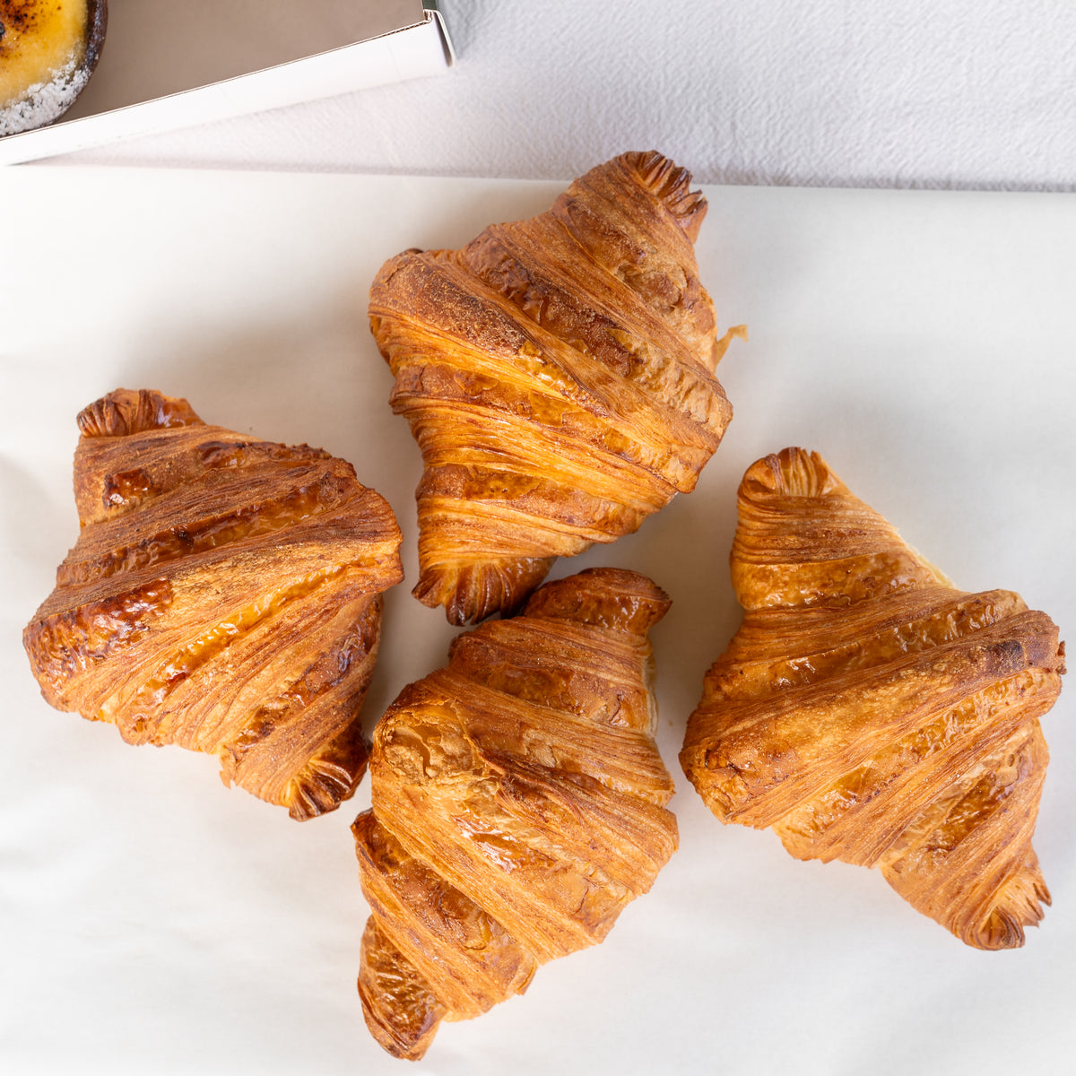 Four golden-brown flaky croissants.