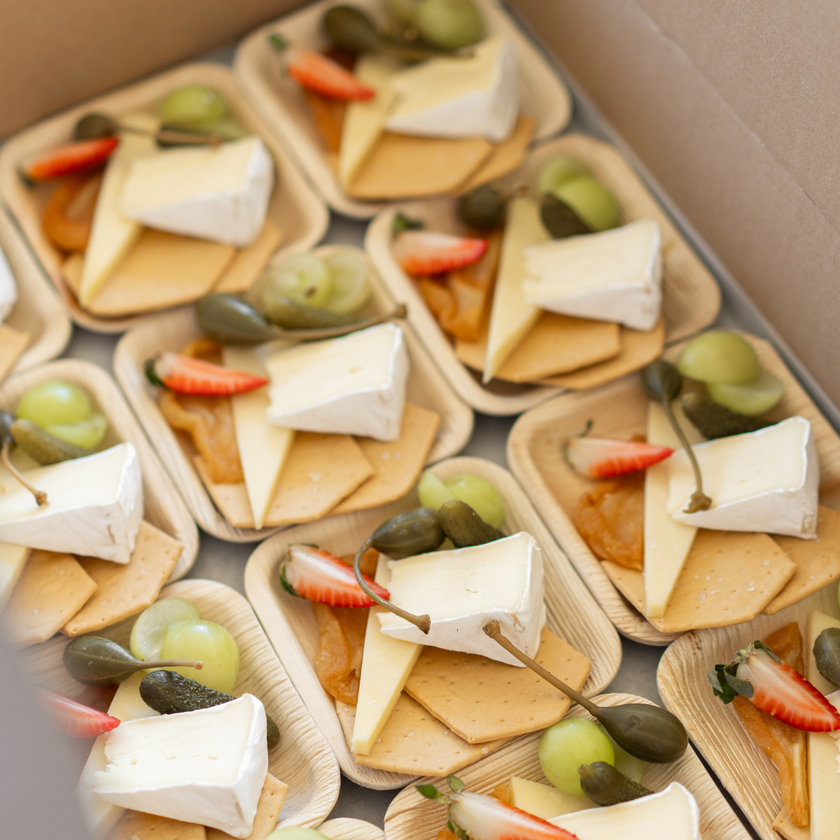 Plated appetizers with cheese, crackers, and fruit on a tray.