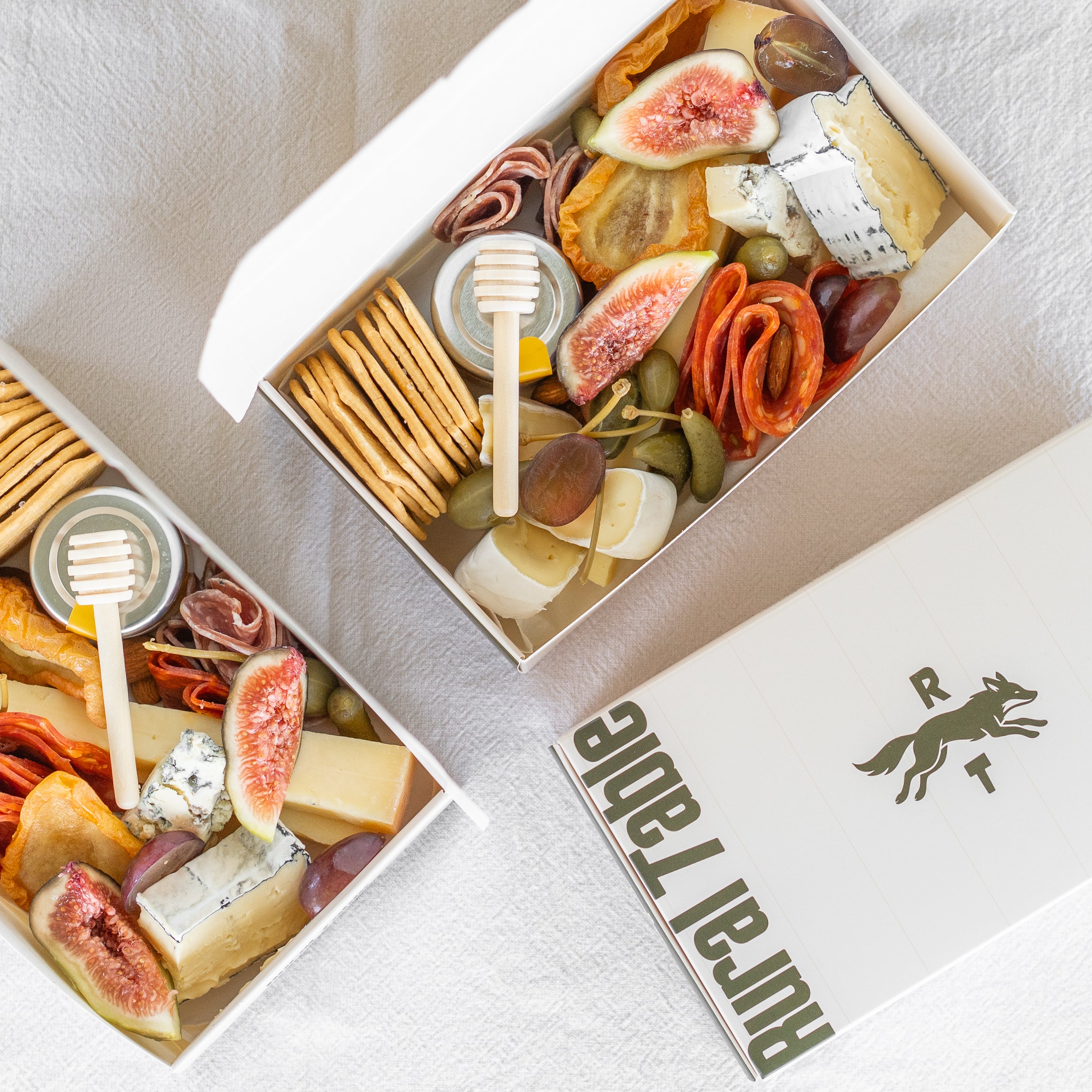 Gourmet food box with figs, cheese, and crackers in a box labeled 'Rural Table'.