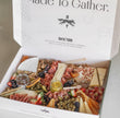 charcuterie board assortment, including sliced cheeses, cured meats, crackers, fruit, olives, nuts, and small jars of spreads. 