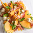 Plated dish of melon salad with prosciutto and mozzarella